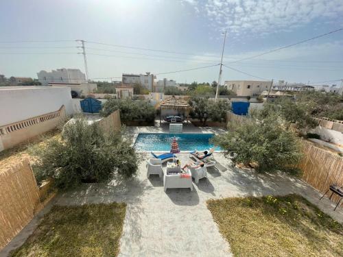 a swimming pool with two people laying on chairs in a backyard at Djerba 7 in Aghīr