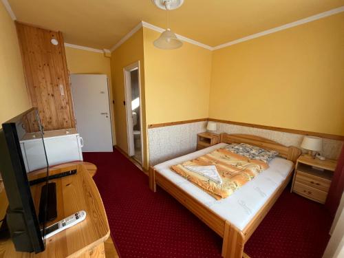 a small bedroom with a bed and a television at Gyógygödör Vendégház in Szekszárd