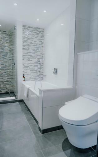 a white bathroom with a tub and a toilet at Hyatt Regency London Albert Embankment in London