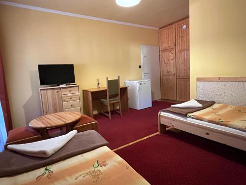 a room with two beds and a desk with a television at Gyógygödör Vendégház in Szekszárd