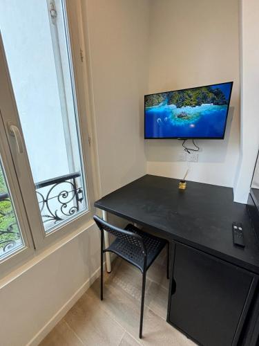 Cette chambre comprend un bureau noir et une télévision murale. dans l'établissement Studio Luxe Paris, à Clichy