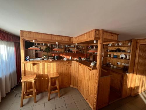 a kitchen with wooden cabinets and a bar with stools at Gyógygödör Vendégház in Szekszárd