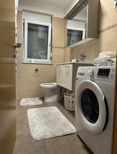 a bathroom with a washing machine and a toilet at Apartman Mara in Solin