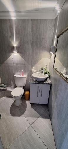 a bathroom with a toilet and a sink and a mirror at 210 at Beach in Strand