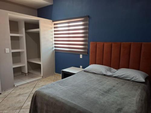 ein Schlafzimmer mit einem Bett und einer blauen Wand in der Unterkunft Departamentos La roca D2 in La Peñita de Jaltemba