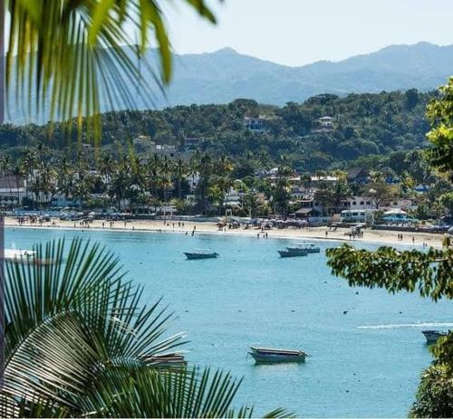 a beach with boats in the water and people on it at Departamentos La roca D2 in La Peñita de Jaltemba