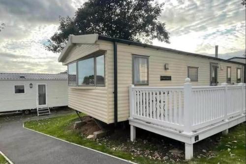 a mobile home with a porch and a white fence at 3 Bed-Sleeps 8-Pet Friendly-Parking-Sea View in Exmouth
