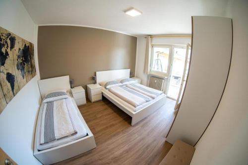 a small room with two beds and a window at Flow Apartments WOLKENSTEIN in Merano