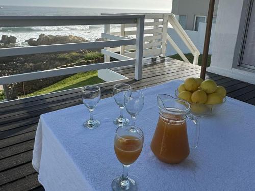 a table with three wine glasses and a bowl of fruit at Waters Edge Beach House in Sea View