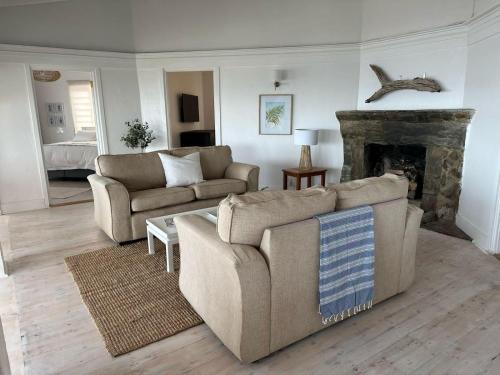 a living room with two couches and a fireplace at Waters Edge Beach House in Sea View