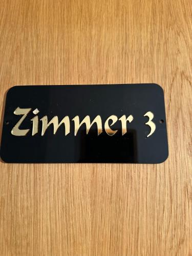 a black sign with the word zimmer on a wooden door at Ferienhaus Löwenherz in Pommern