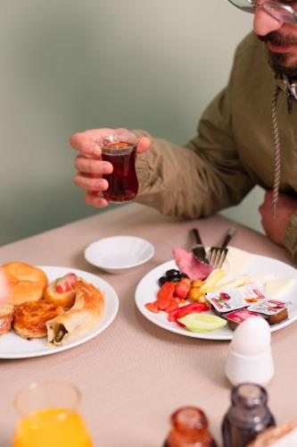 a person holding a glass of drink next to plates of food at Polek Hotel in Canakkale