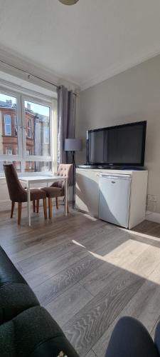 a living room with a table and a large television at Carrick - One Bed Apartment in Largs