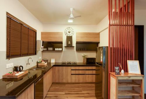 a kitchen with wooden cabinets and a stainless steel refrigerator at Nistula Luxury Pool Villa C3 in Assagao in Assagao