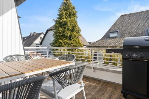 a balcony with a table and chairs and a grill at JASPER - Balkon, BBQ, PS5, Flexbetten - Zentral & 15min in Willingen in Brilon