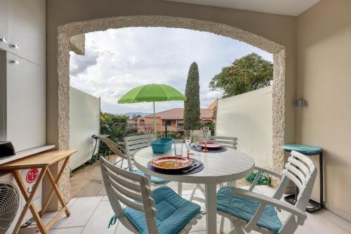 d'une terrasse avec une table, des chaises et un parasol vert. dans l'établissement Les Aigues Marines- Face au Port Climatisé, à Saint-Cyr-sur-Mer