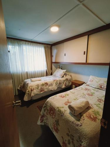 a hotel room with two beds and a window at Hostal & Cabañas Don Juan in Villarrica