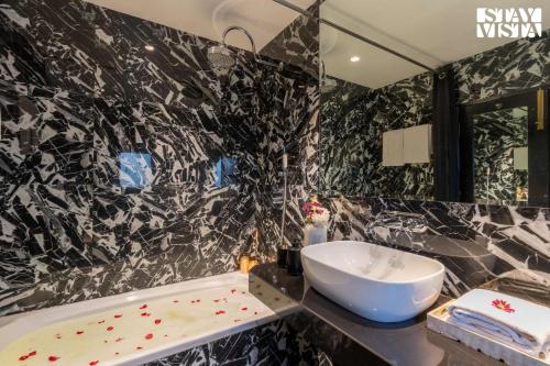 a black and white bathroom with a sink and a tub at Mehta Mansion by StayVista - A Villa with a Swimming Pool and Pool Table in Lonavala