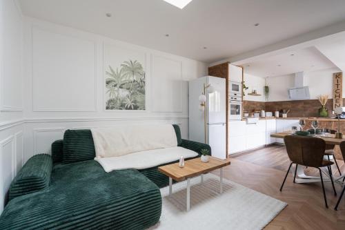 un salon avec un canapé vert et une cuisine dans l'établissement Charming house with a hot tub, à Saint-Ouen
