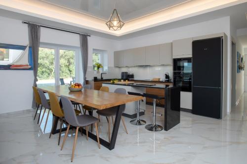 a kitchen with a wooden table and chairs at Villa Sunset, stunning villa rental in Corfu by PosarelliVillas in Perítheia