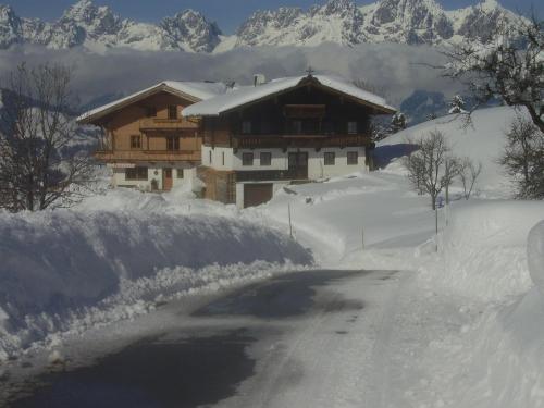a house on a snow covered road next to a mountain at Hahnenkammblick in Kitzbühel