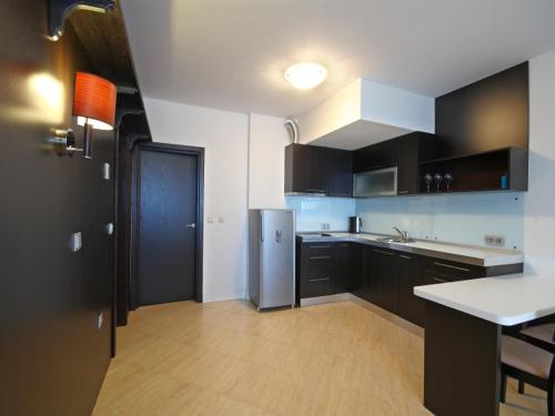 a kitchen with black cabinets and a stainless steel refrigerator at PSB Apartments in Midia Resort Aheloy in Aheloy
