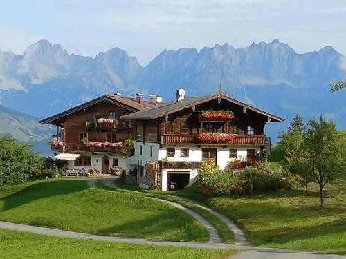 a house on a hill with mountains in the background at Hahnenkammblick in Kitzbühel