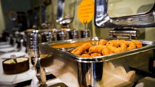 a metal tray filled with deep fried food on a machine at Hotel Ajanta - Colonial Charm Award Winning Luxury Hotel in the Heart of the City in New Delhi