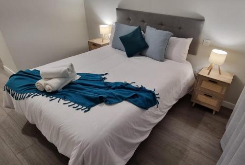 a bedroom with a large white bed with blue sheets and pillows at Torrejón Suites in Torrejón de Ardoz