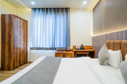 a bedroom with a white bed and a blue curtain at Hotel De Grand Dwarka-Near Jaipur Airport in Jaipur