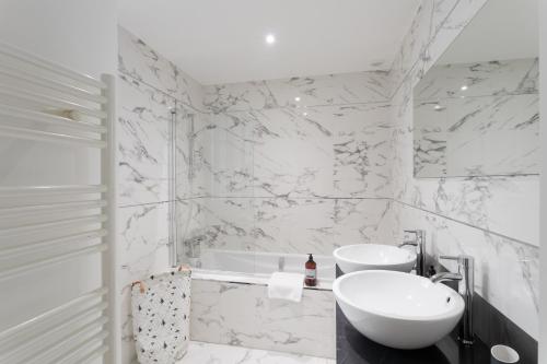 a white bathroom with a sink and a tub at Din'Art by Cocoonr in Dinard