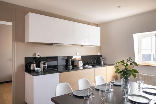 a kitchen with a table and white cabinets at Din'Art by Cocoonr in Dinard