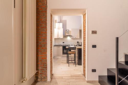 an open hallway leading to a kitchen with a brick wall at Casa Volturno - 5 min dalla stazione in Monza