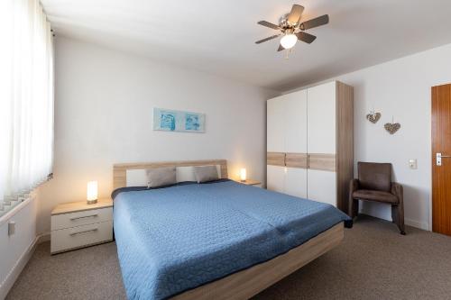 a bedroom with a blue bed and a ceiling fan at Ferienwohnung "Weserblick" Columbus Center in Bremerhaven