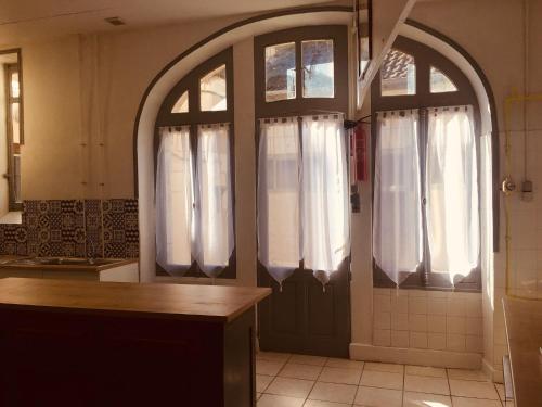 - une cuisine avec une porte voûtée et des rideaux blancs dans l'établissement Le Lion d'Or chb double wifi 4, à Écueillé