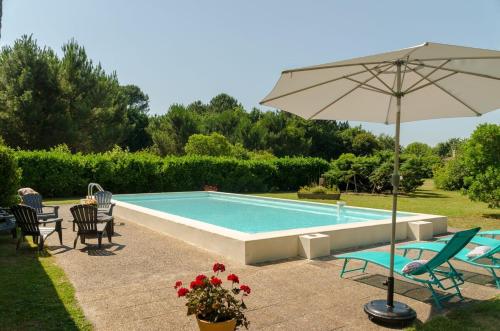 - une piscine avec un parasol, des chaises et une table dans l'établissement Maison de Maître Piscine & Pool House, à Biscarrosse