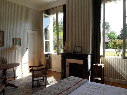 - une chambre avec un lit, une cheminée et des fenêtres dans l'établissement Maison de Maître Piscine & Pool House, à Biscarrosse