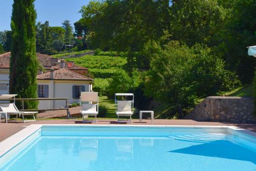 a swimming pool with two chairs and a house at I Cipressi by Halldis in Colognola ai Colli