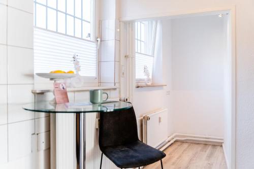 a small kitchen with a glass table and a black chair at Schiffskajüte in Flensburg