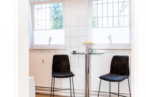 two chairs and a table in a room with windows at Schiffskajüte in Flensburg