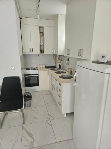 a white kitchen with a black chair and a refrigerator at M&S Lux in Mladenovac