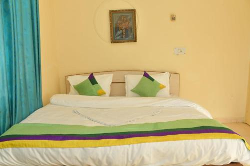 a bed with green and colorful pillows on it at The Hidden Cove in Bhīm Tāl