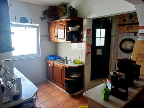 a kitchen with wooden cabinets and a sink and a window at Hostel Nature in Zambujeira do Mar
