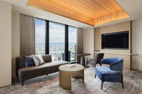 a living room with a couch and chairs and a tv at THE OSAKA STATION HOTEL, Autograph Collection in Osaka