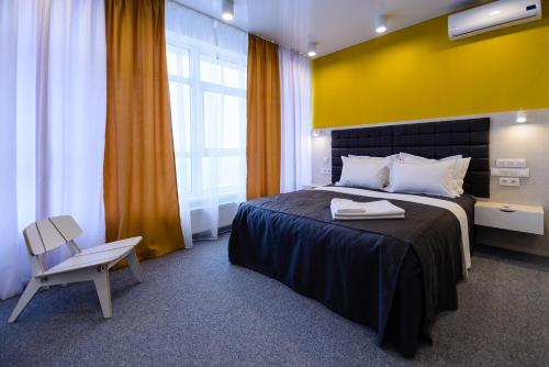 um quarto com uma cama e uma cadeira e uma parede amarela em Partner Guest House Klovs'kyi em Kiev