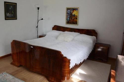 a wooden bed with white sheets in a bedroom at Serbina in Kandalica