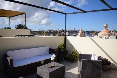 a patio with a couch and a table on a roof at Cottonera Lines Boutique Holiday Accomodation in Cospicua