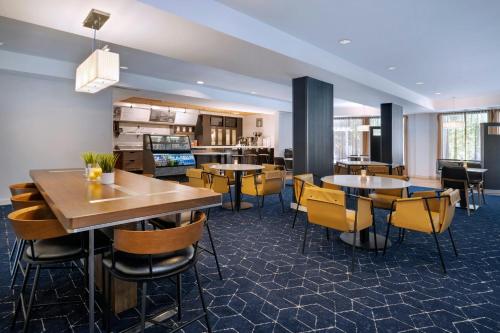 a restaurant with tables and chairs and a kitchen at Courtyard Tampa North / I-75 Fletcher in Tampa