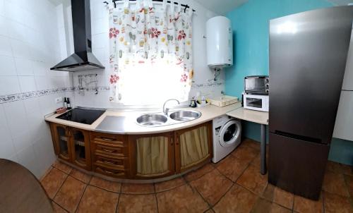 Una pequeña cocina con fregadero y refrigerador. en Alojamiento valeria, en Arroyo Frío