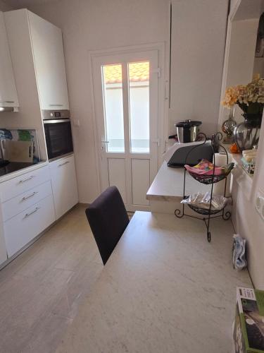 a kitchen with white cabinets and a table with a chair at Apartment sofia sea view in Vrasná